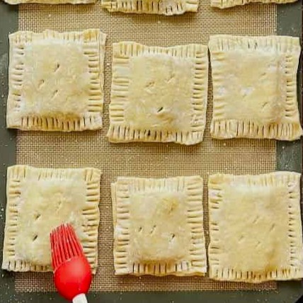 Brushing pastelitos with egg wash and baking
